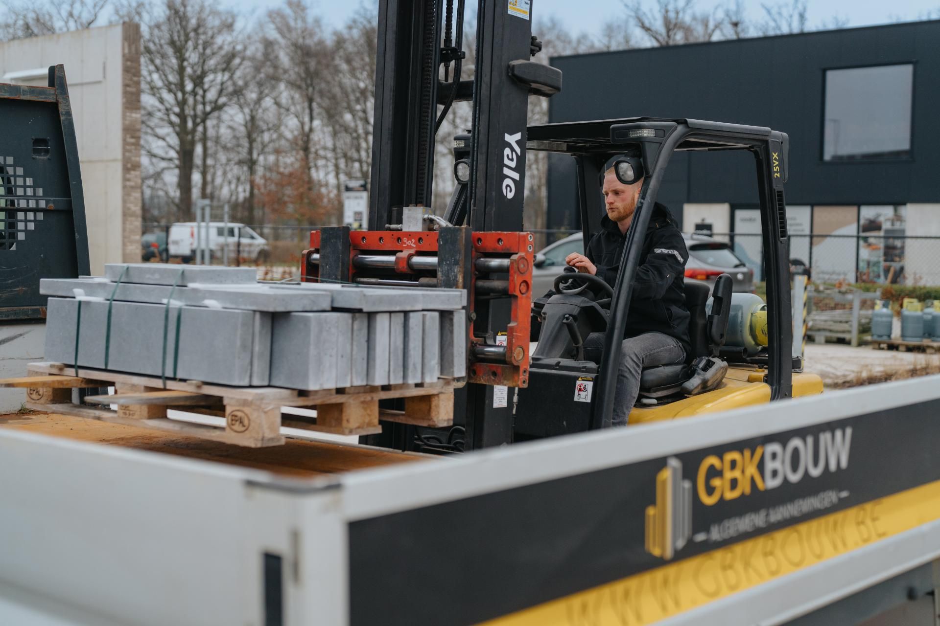 Medewerker van GBK Bouw op een heftruck met bouwmaterialen
