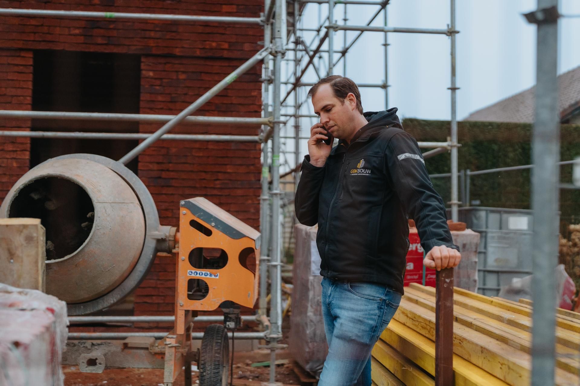 Medewerker van GBK Bouw telefoneert op de werf