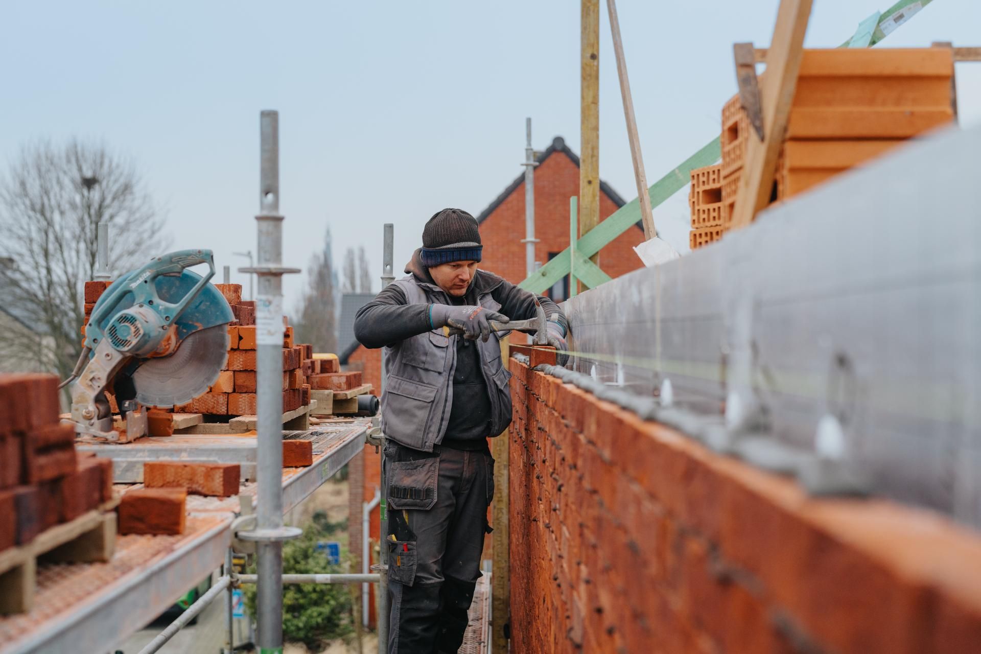 Metselaar GBK Bouw aan het werk op een steiger tijdens werkzaamheden van een casco woonproject.